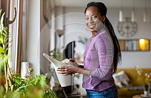 Beautiful woman watering plants at home